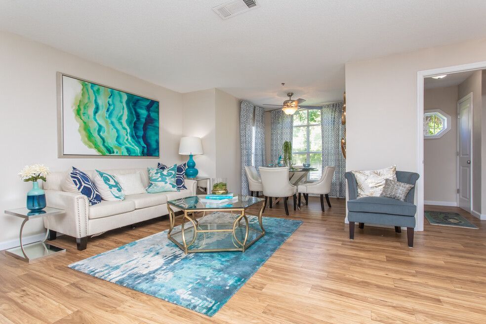 Empty white living room with wood floors, recessed lights, and a staircase on the left