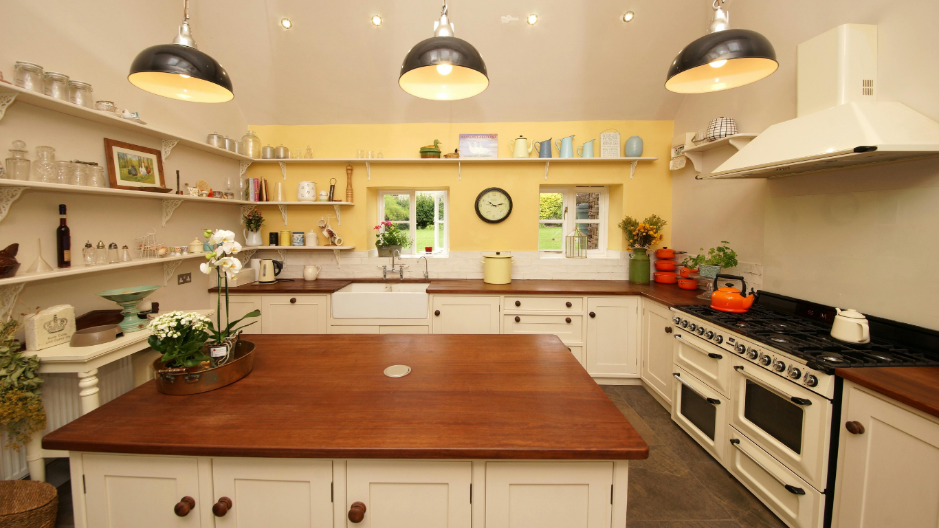 A rustic kitchen with white cabinets, a large wooden island, open shelving, and a range cooker against a yellow wall.