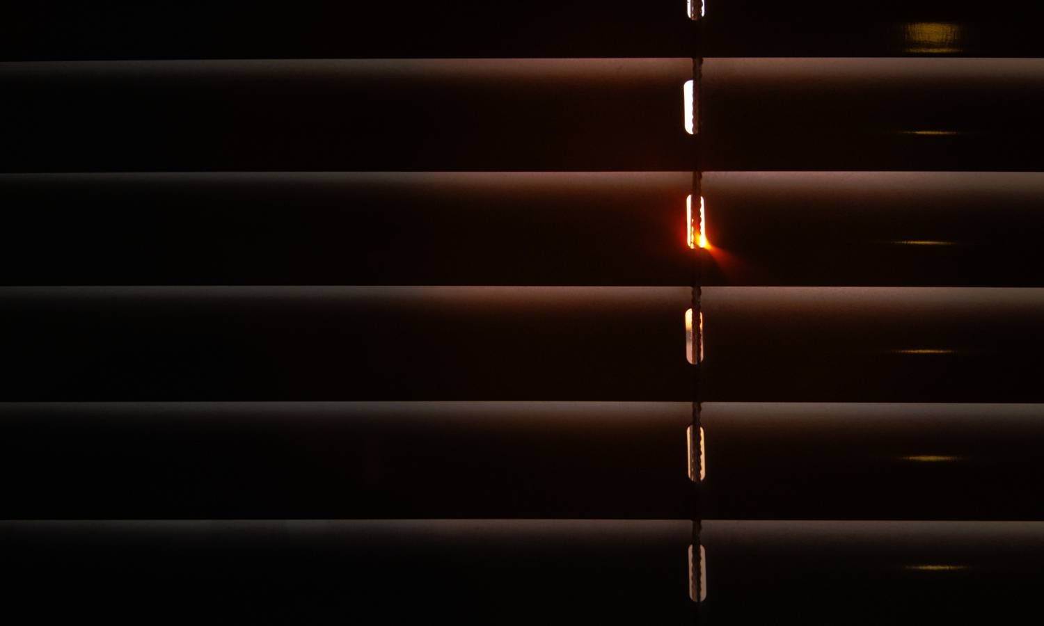 Light gaps peaking through the slats of window blinds in a home near Seattle, WA
