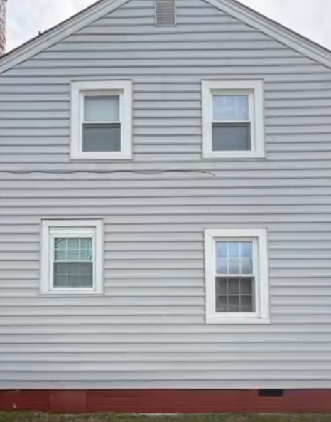 Gray house exterior with four windows and red foundation trim