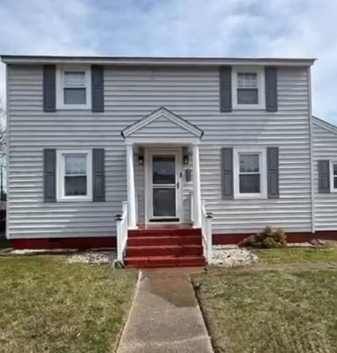 Gray two-story house with white trim, red front steps, and a concrete walkway leading to the door