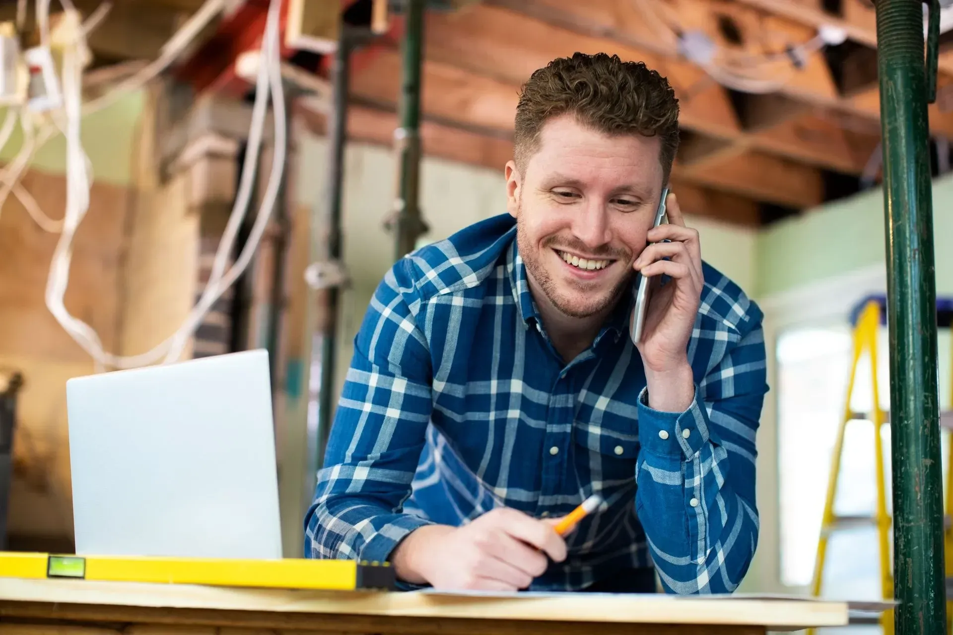 a man in a plaid shirt is talking on a cell phone