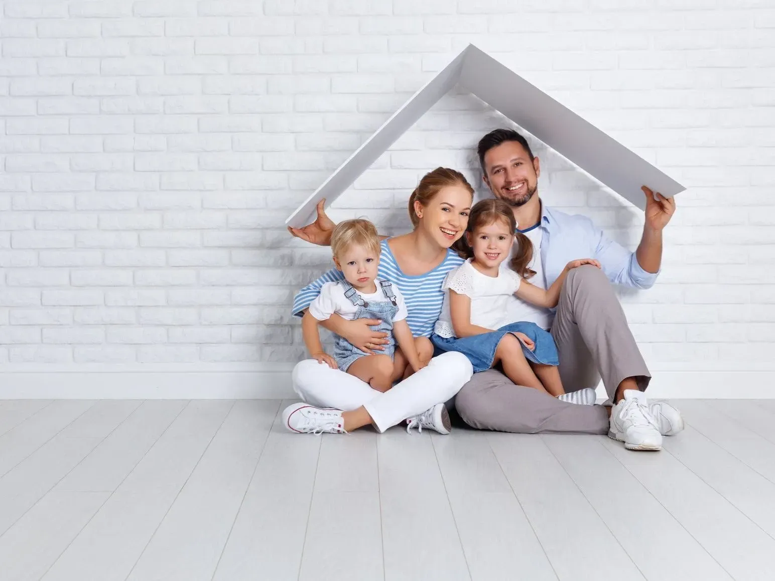 a family sits under a cardboard house roof