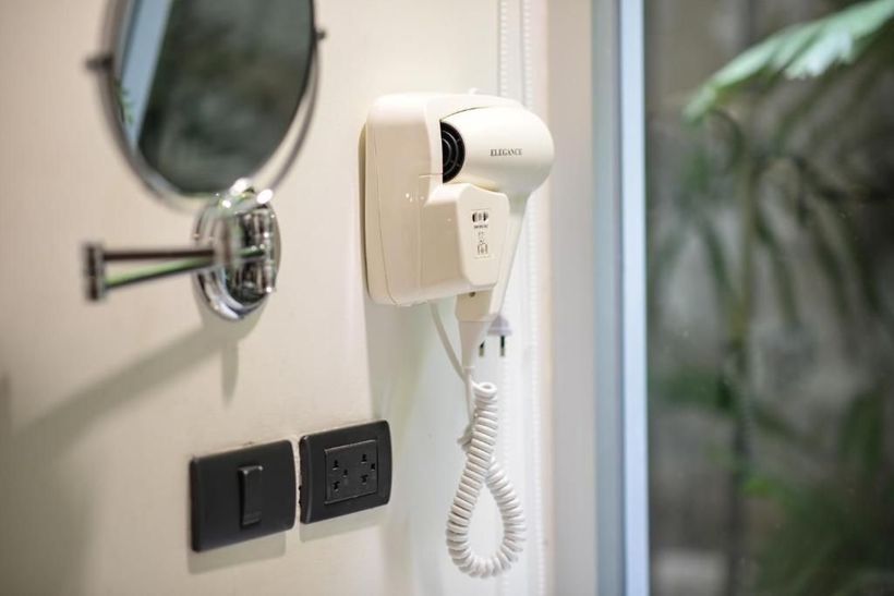 A hair dryer is hanging on a wall next to a mirror.