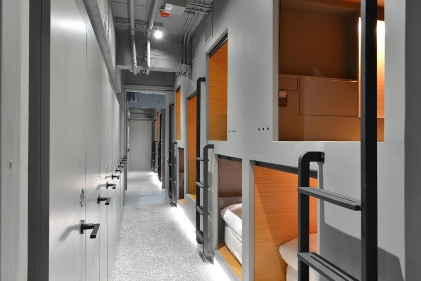 A long hallway filled with bunk beds and a toilet.