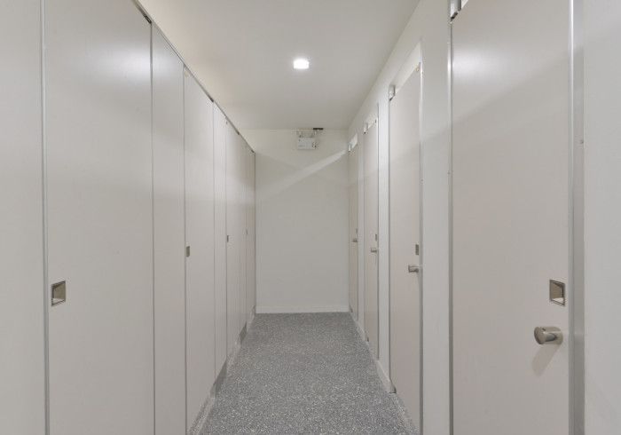 A long hallway with white doors and a gray carpet.