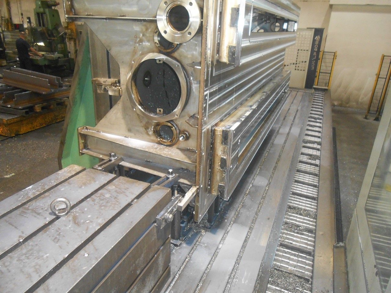 Serbatoi e tubazioni industriali in acciaio inossidabile in un ambiente di fabbrica pulito, con macchinari sul pavimento.