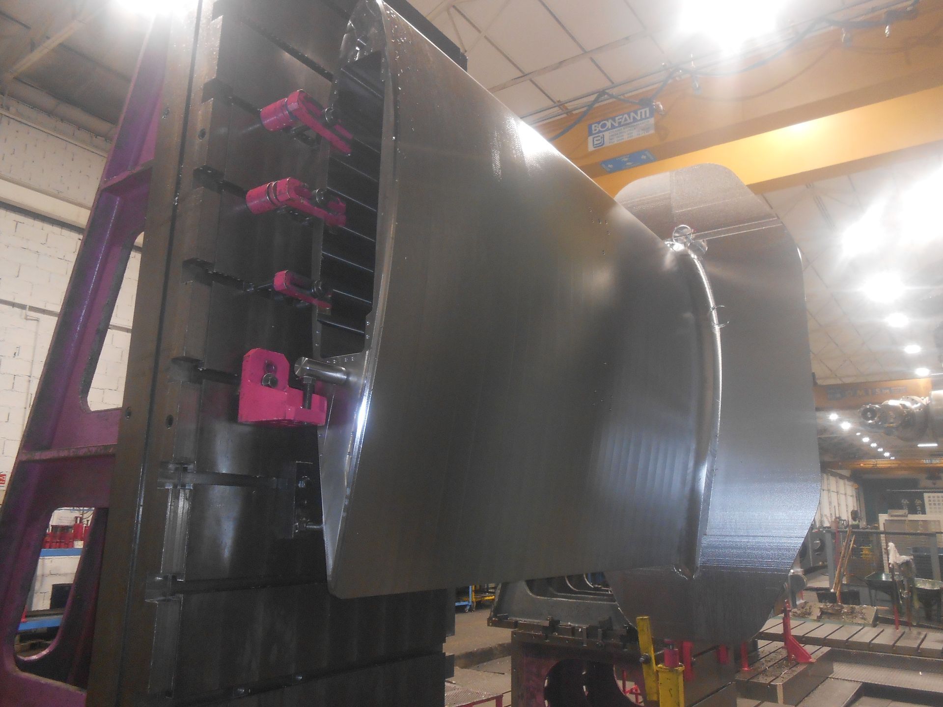 Un grande componente di una macchina industriale viene lavorato su una fresatrice CNC in un'officina di fabbrica.