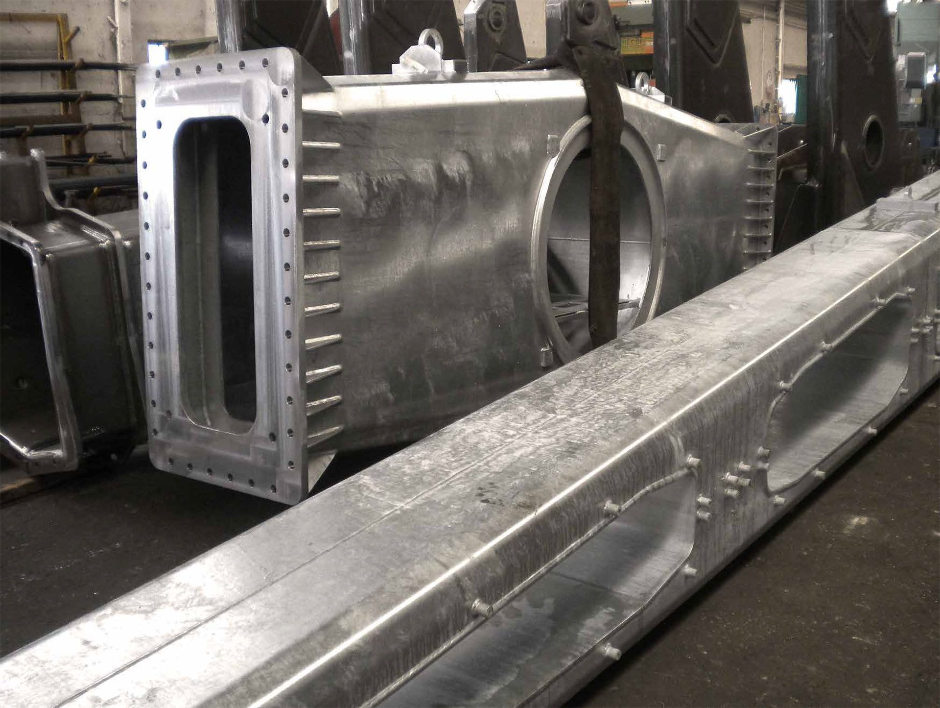 Grandi condotti metallici industriali e prese d'aria rettangolari in un'officina o nel pavimento di una fabbrica.