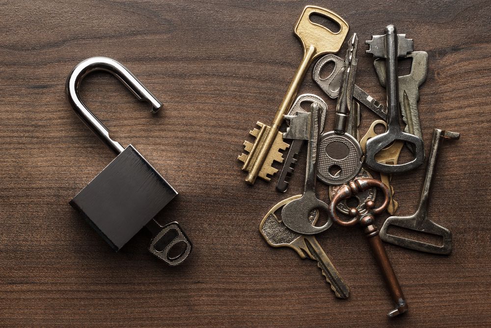 Open Padlock Next to A Pile of Various Keys on A Wooden Surface — CQR Locksmiths in Warialda, NSW