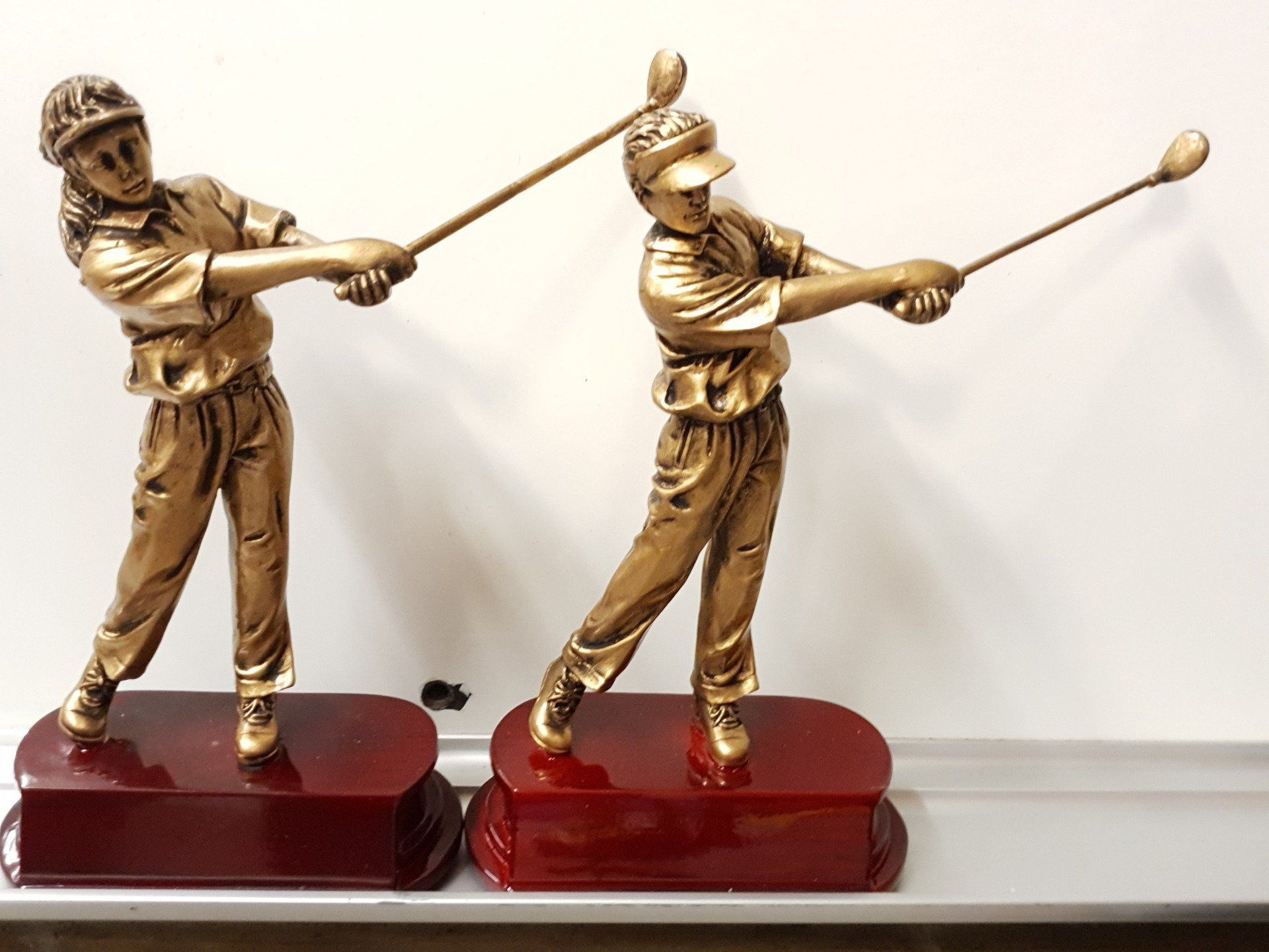Two Gold Golf-Player Statues On Red Wooden Bases — CQR Locksmiths In Moree, NSW