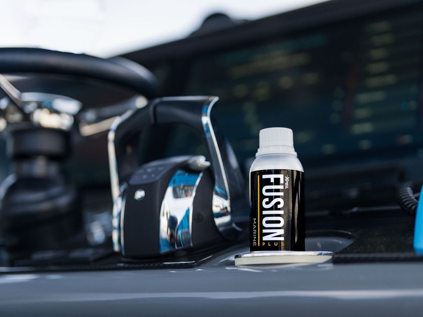 Fusion water bottle on a car dashboard beside a camera, with a blurry screen in the background