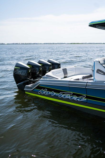 Speedboat on calm water with three outboard motors and blue-green racing stripes
