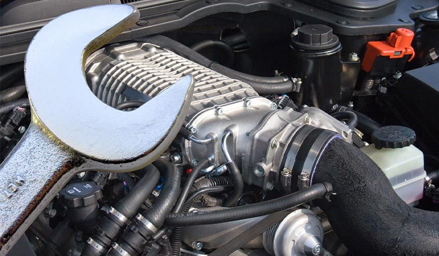 A wrench is sitting on top of a car engine
