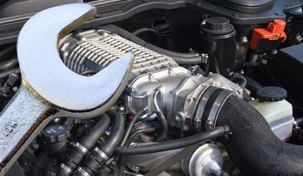 A wrench is sitting on top of a car engine