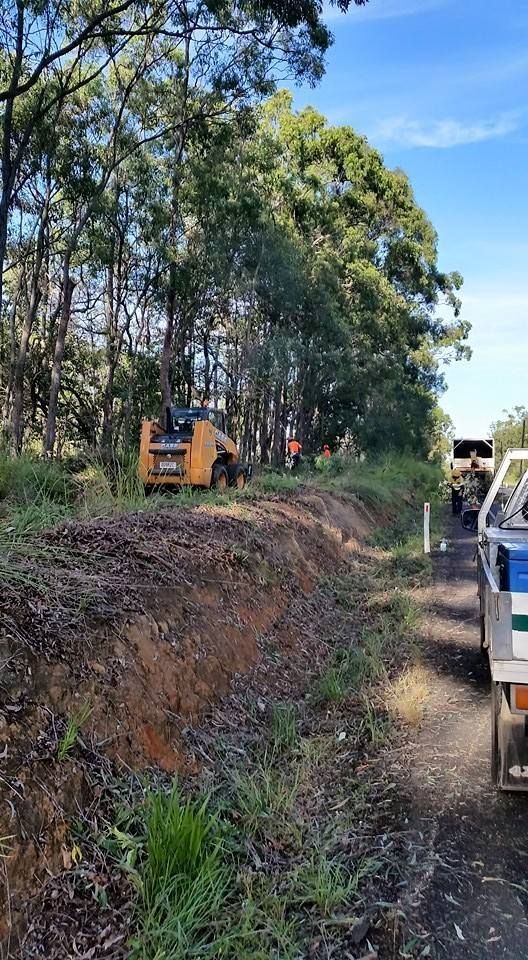 A Bulldozer Is Driving Down A Dirt Road Next To A Truck — A1 Tree Service in Agnes Waters, QLD