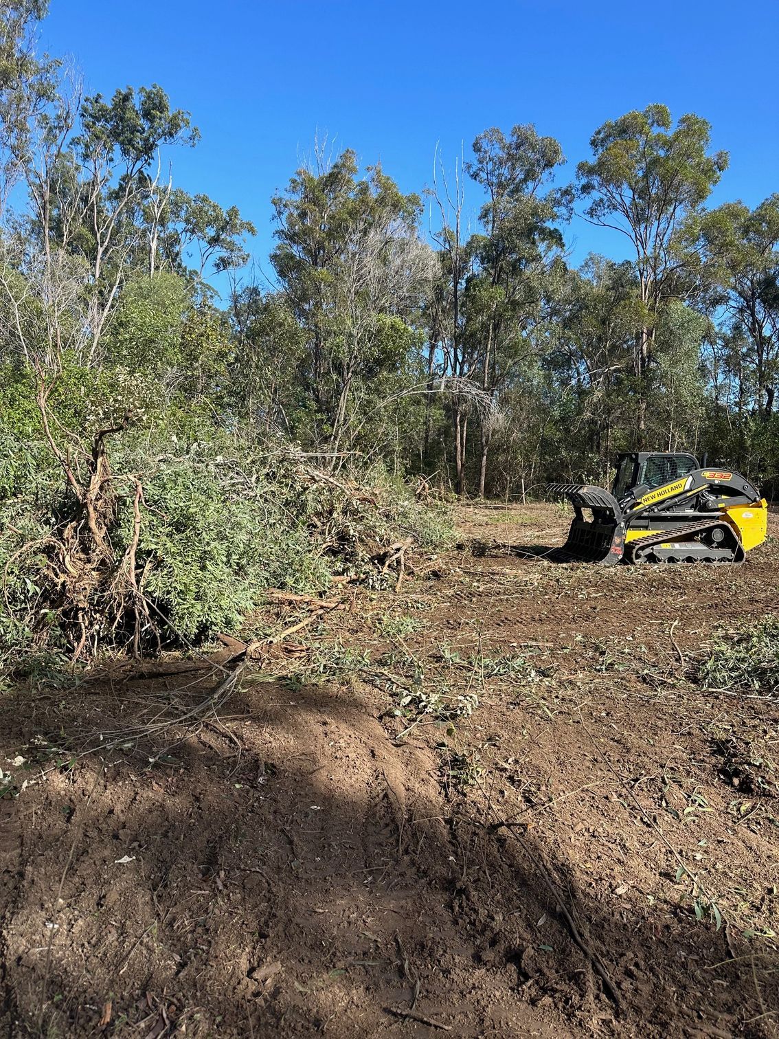 A Yellow Excavator Parked on the Side of a Dirt Road — A1 Tree Service in Kensington, QLD
