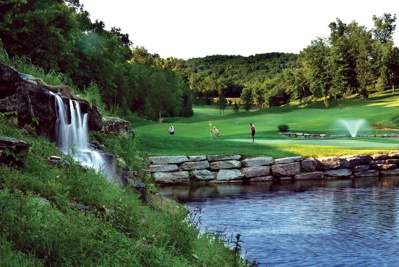 a waterfall is in the middle of a golf course