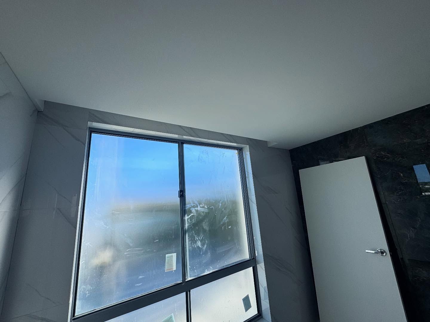 Minimal room with a large frosted window and an open white door on the right.