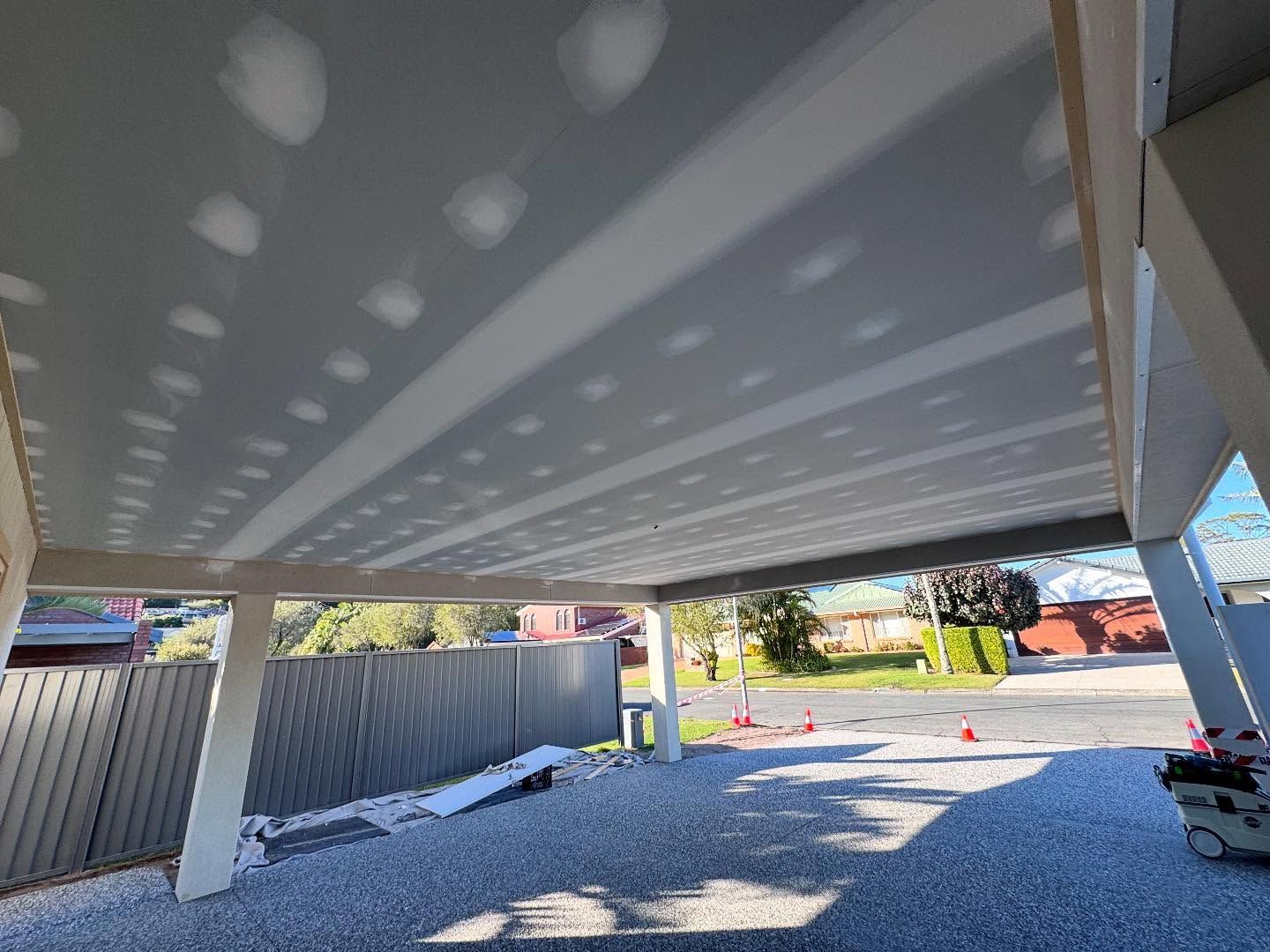 Under-bridge parking area with white ceiling, support columns, and orange cones on the ground