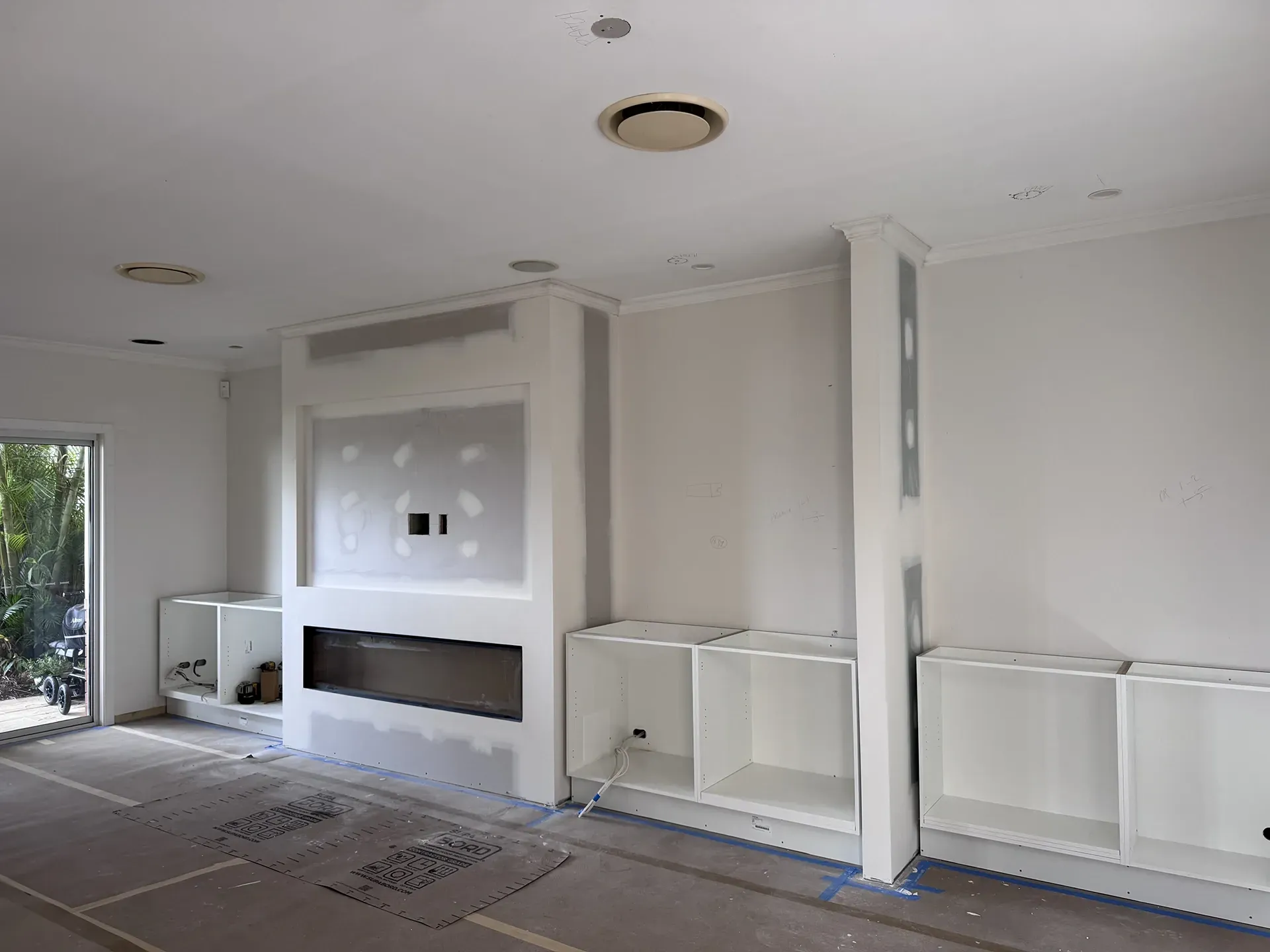 Empty white living room under renovation with built-in fireplace and wall panels installed