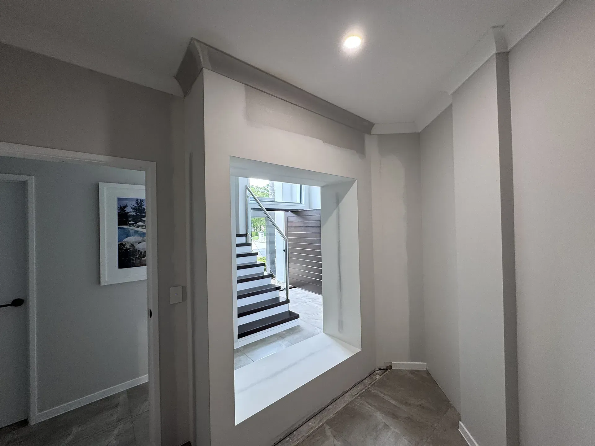 Empty hallway with gray walls, a ceiling light, and a large window view of stairs outside.