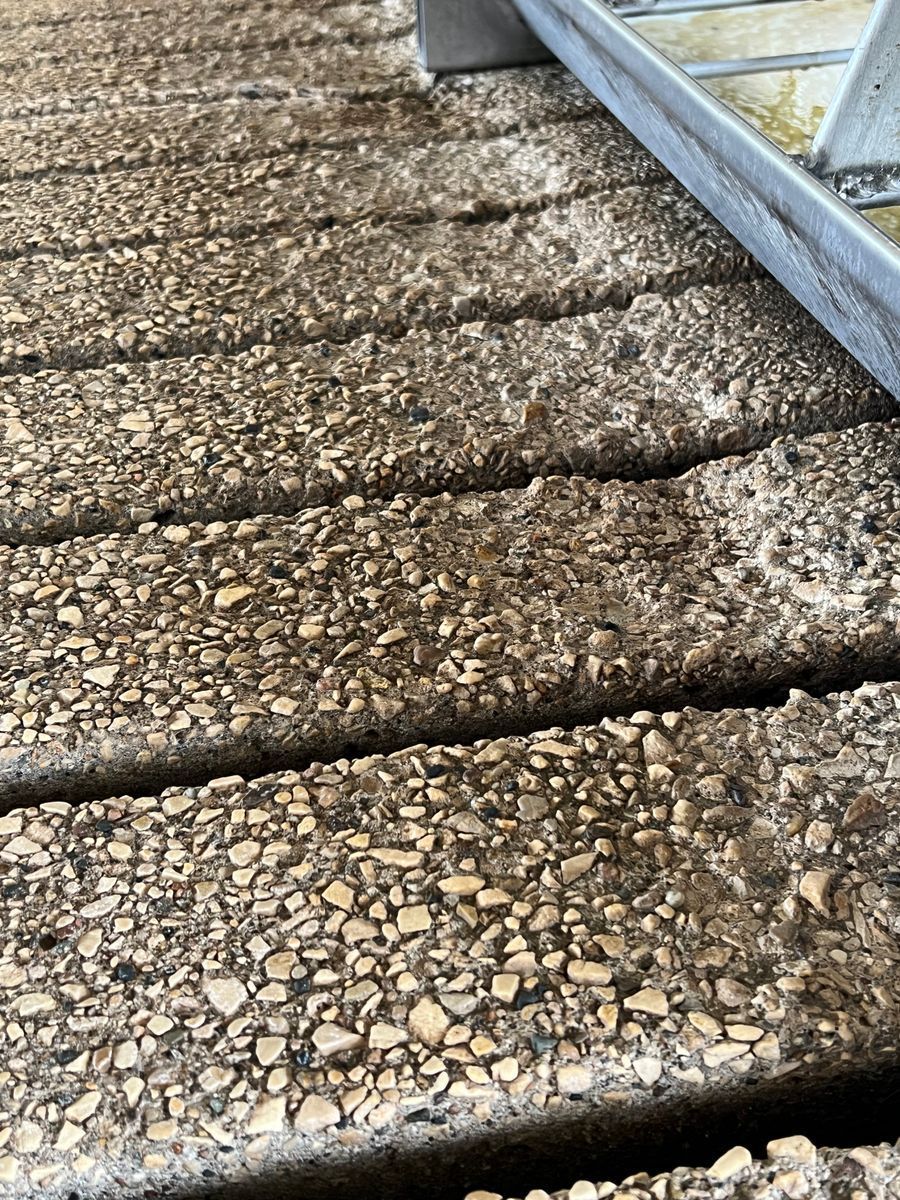 A close up of a concrete staircase with a ladder in the background.