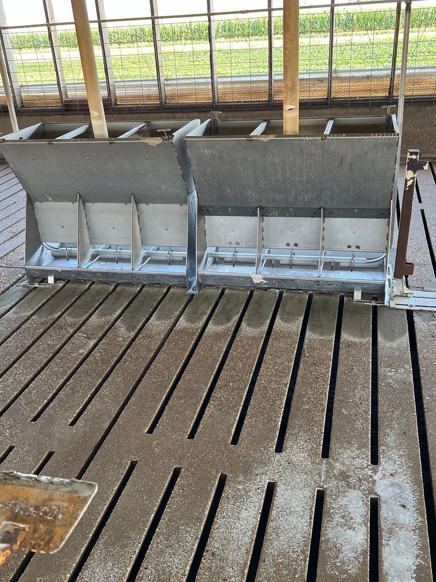 A couple of feeders sitting on top of a dirt floor in a barn.