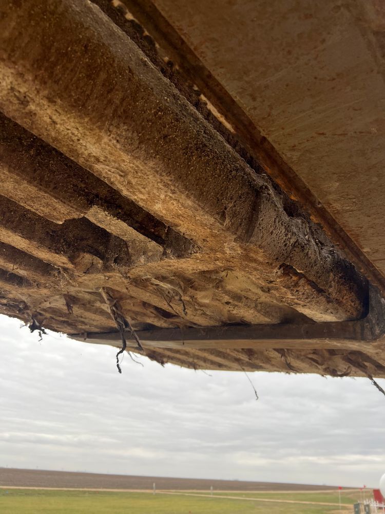 A close up of the underside of a bridge with a field in the background.