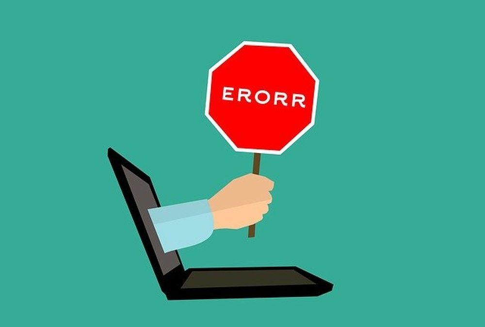 A hand is holding a stop sign in front of a laptop computer.
