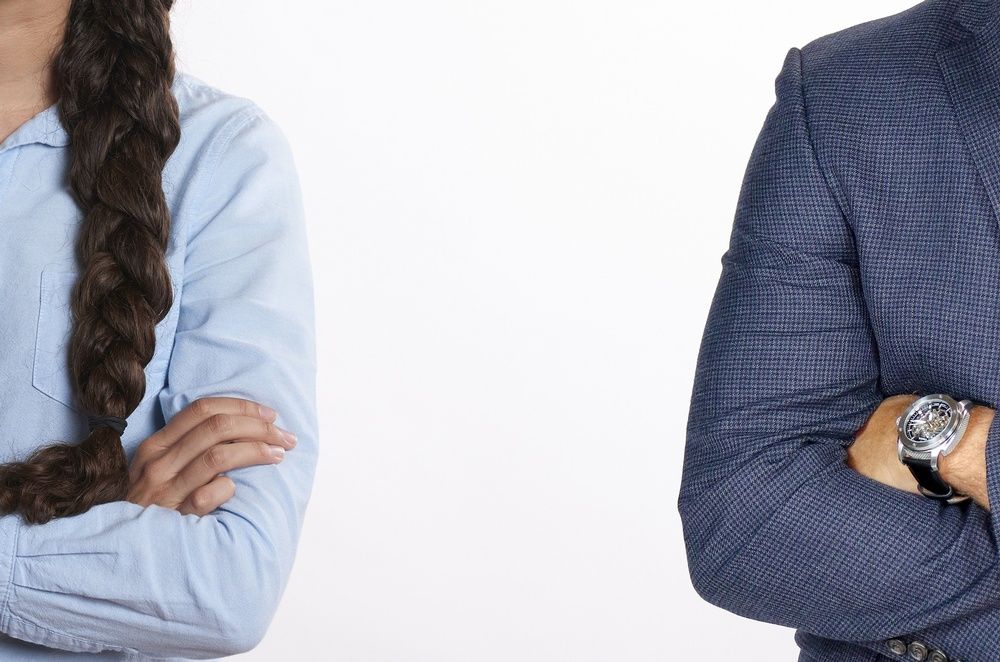 A man and a woman are standing next to each other with their arms crossed.