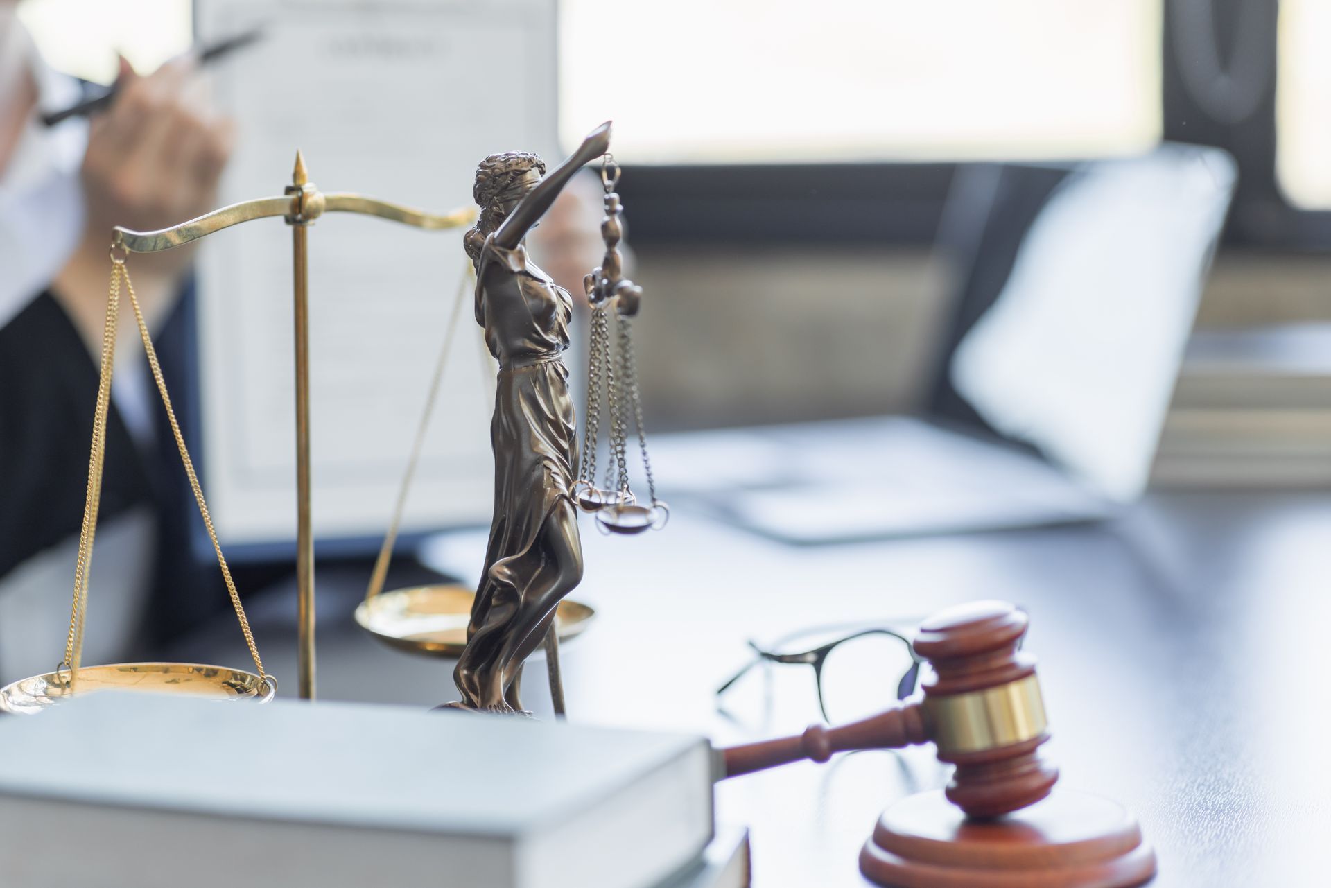 A statue of justice is sitting on top of a book next to a judge 's gavel.
