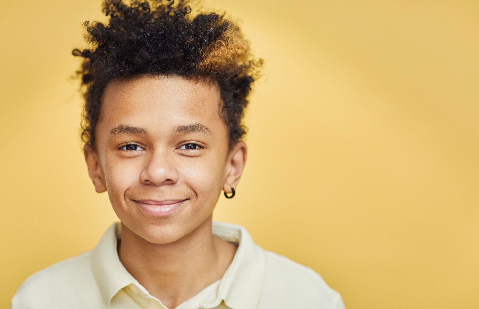 Portrait of a smiling person in a white shirt against a warm yellow background