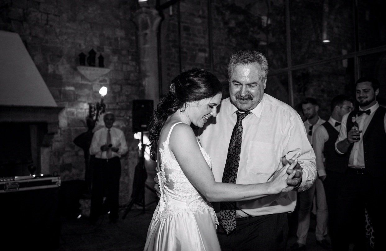 Bride and older man dancing at a dimly lit wedding reception