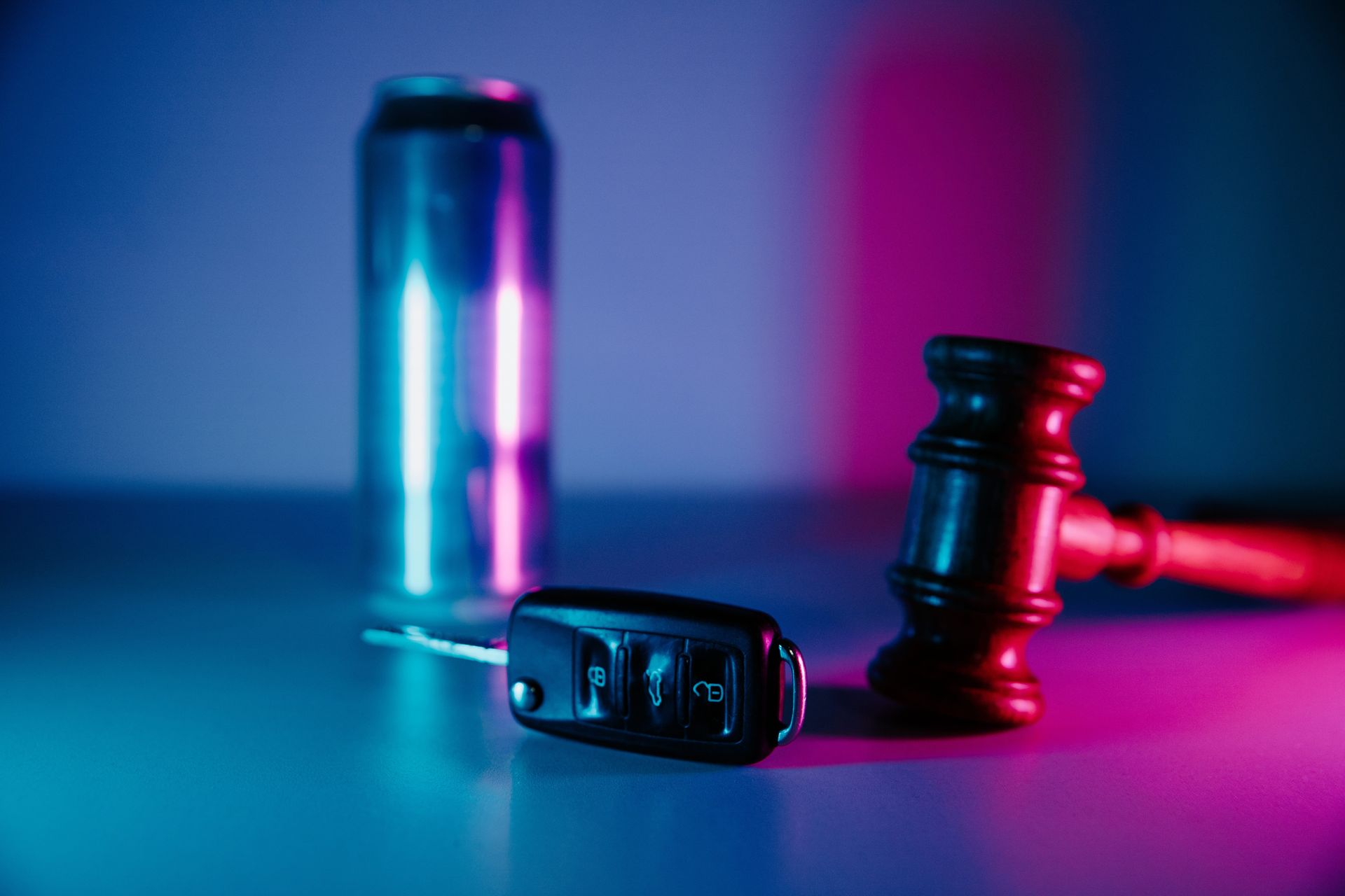 A judge’s gavel, handcuffs, and a canister lit in blue and pink on a dark surface.