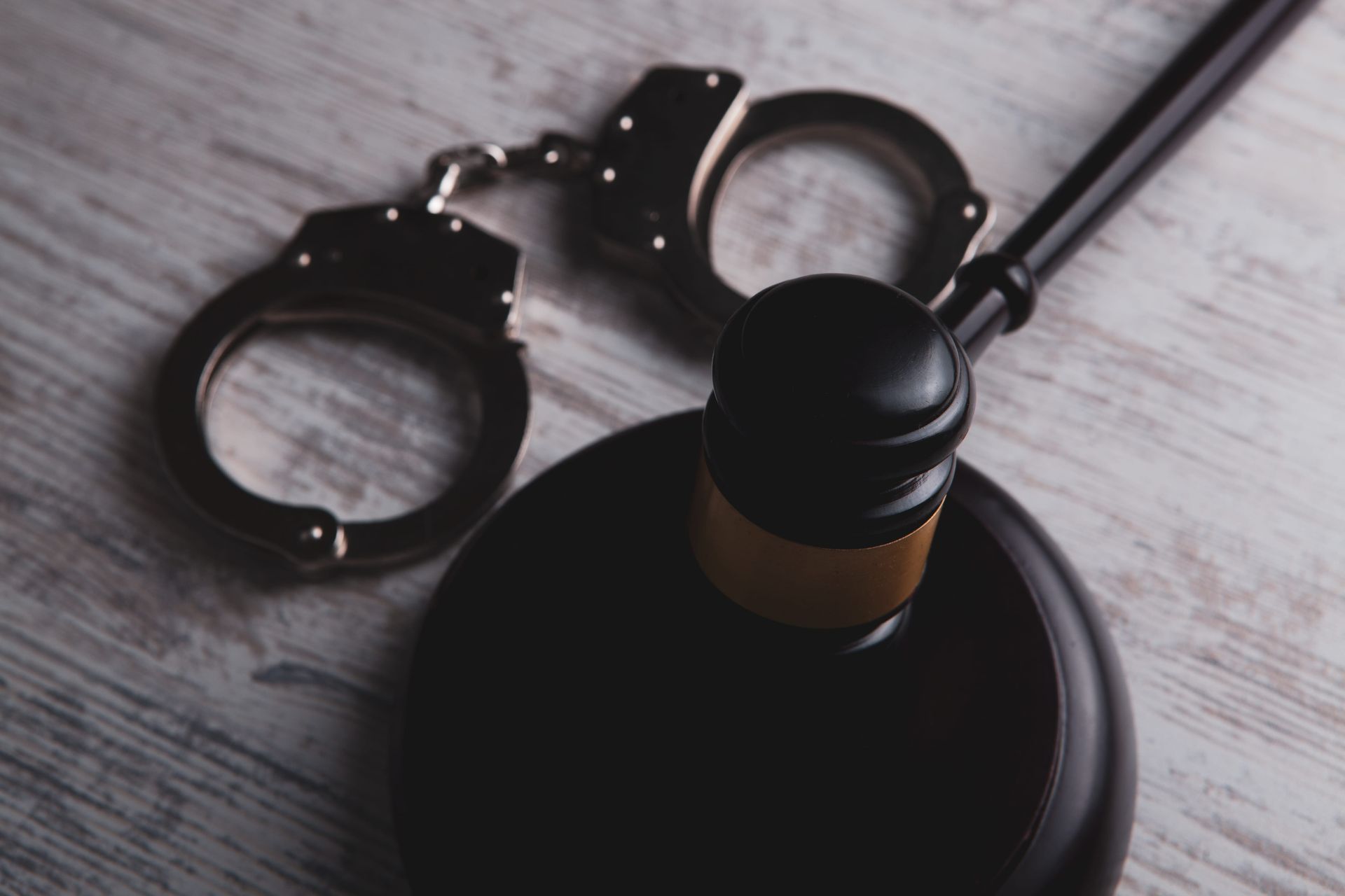 Handcuffs beside a judge’s gavel on a wooden table