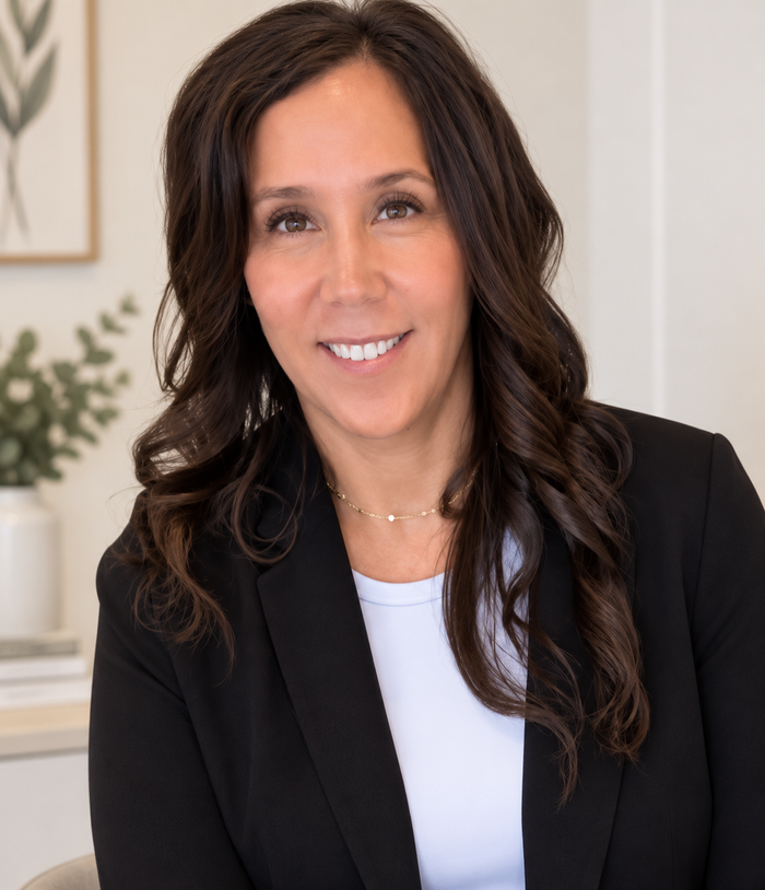 Smiling Amelia in a black blazer and white top in a bright office setting