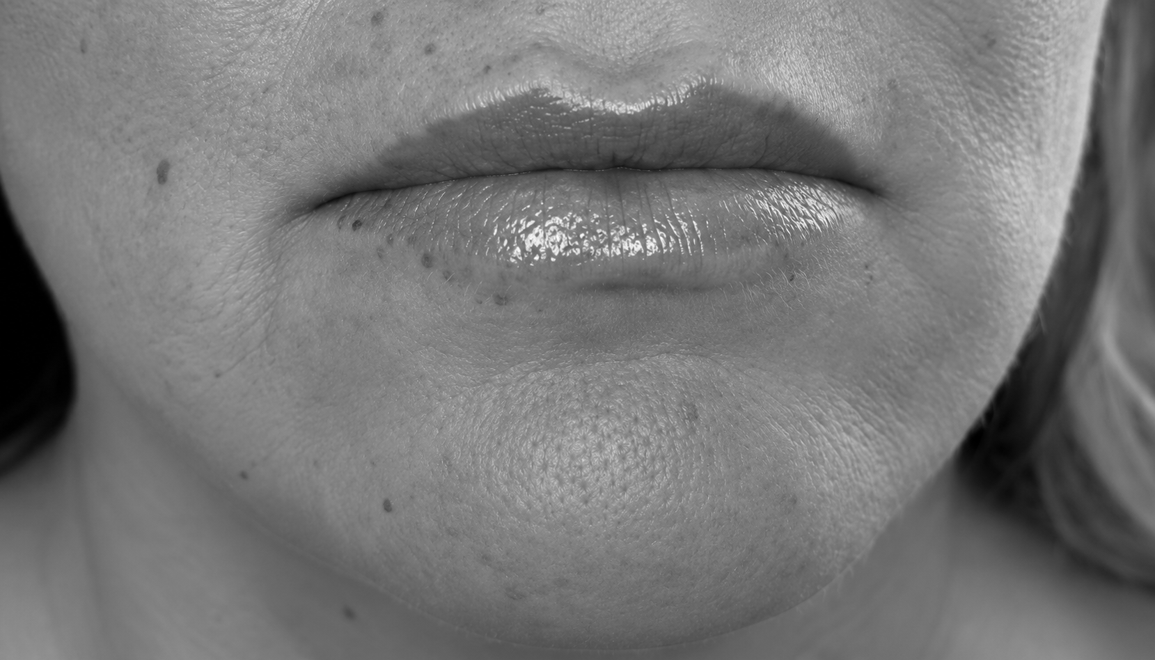 Close-up of a person’s lips and chin with visible facial skin texture in black and white