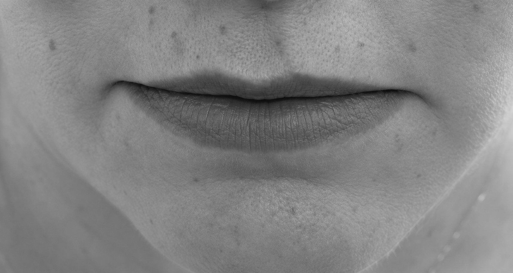 Close-up of a person’s mouth and chin with lips gently closed in grayscale