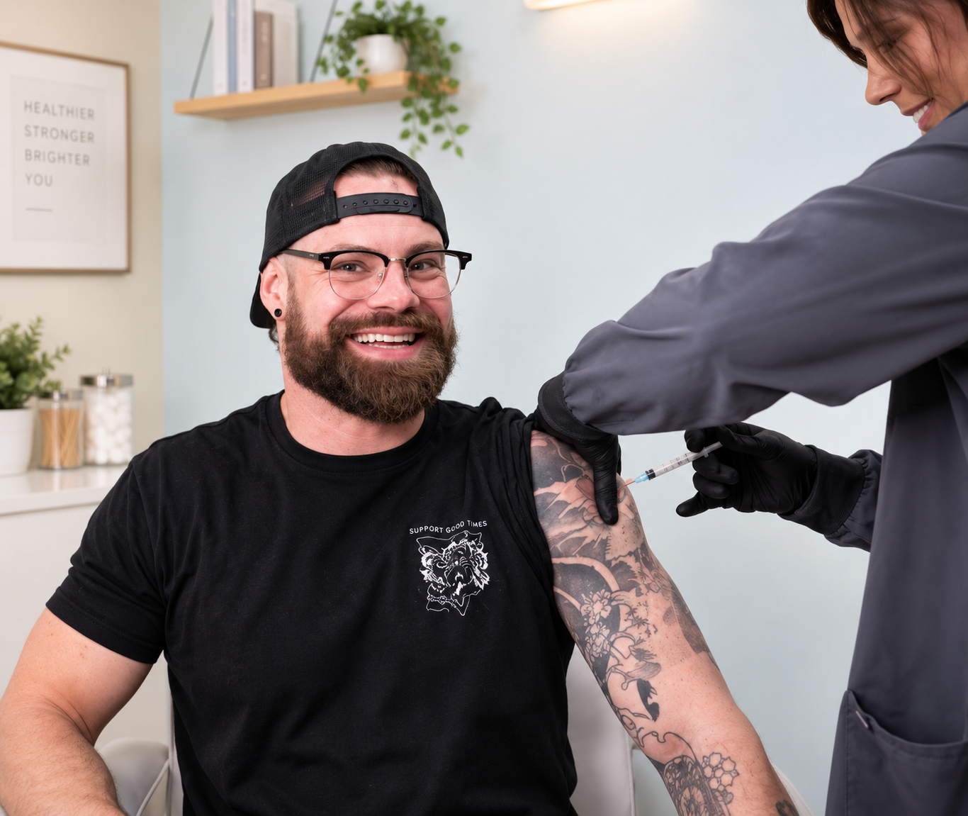Smiling man in black shirt getting an NAD+ injection in his upper arm.