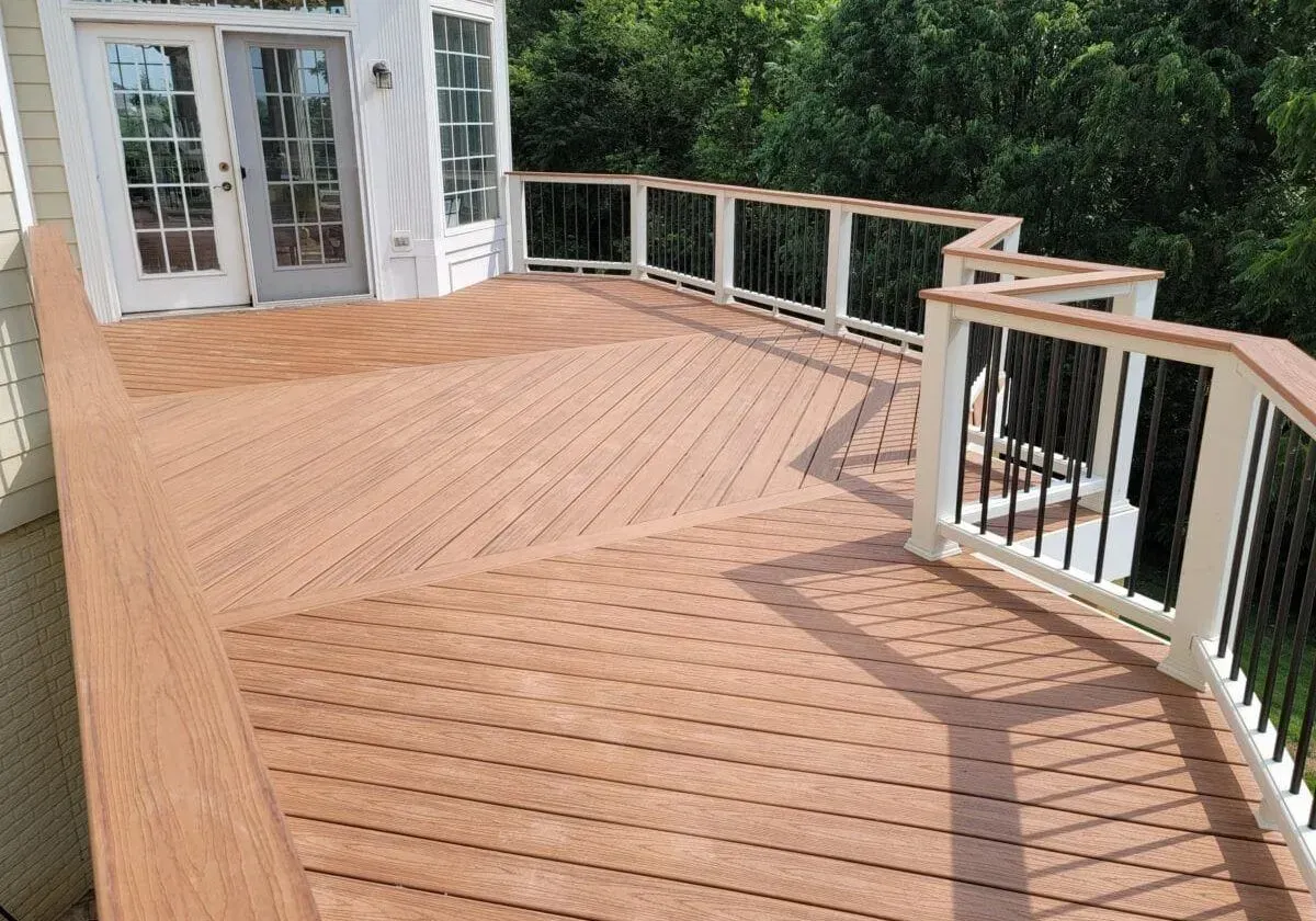 A large wooden deck with a white railing and sliding glass doors