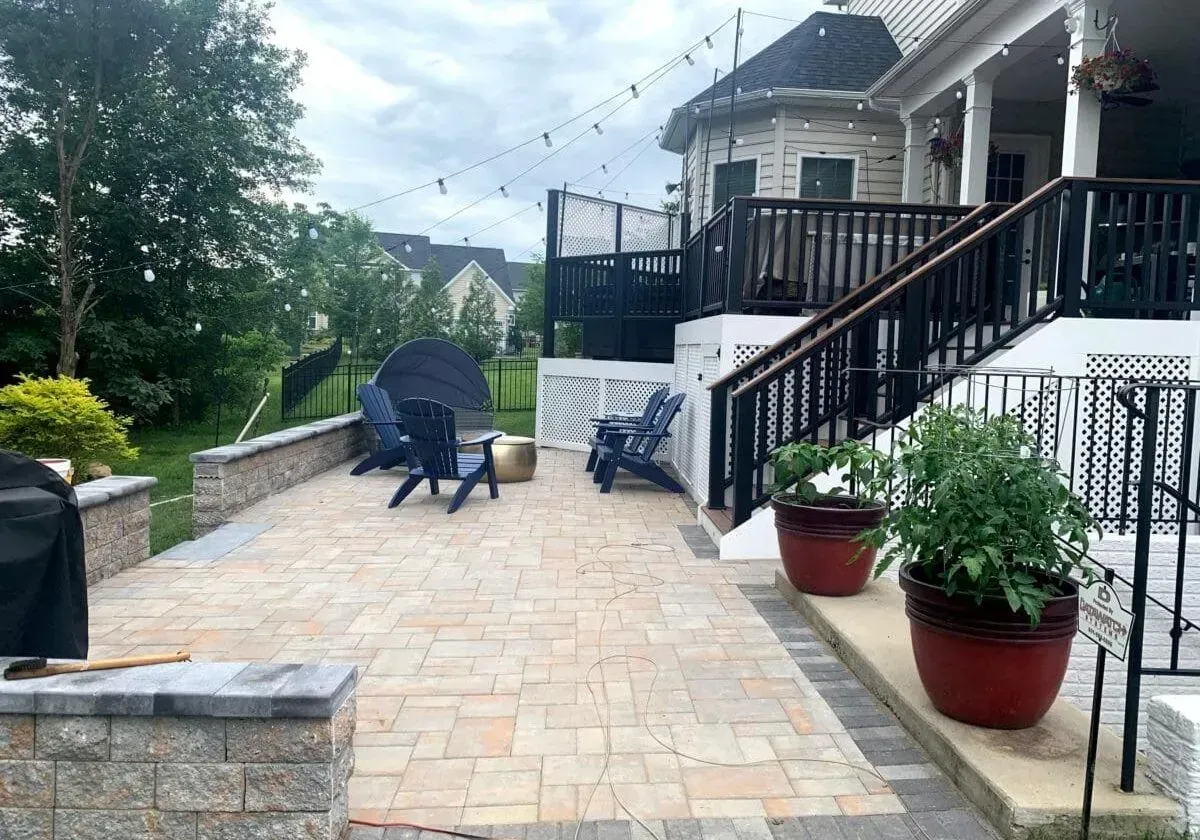 A patio with chairs and potted plants in front of a house.