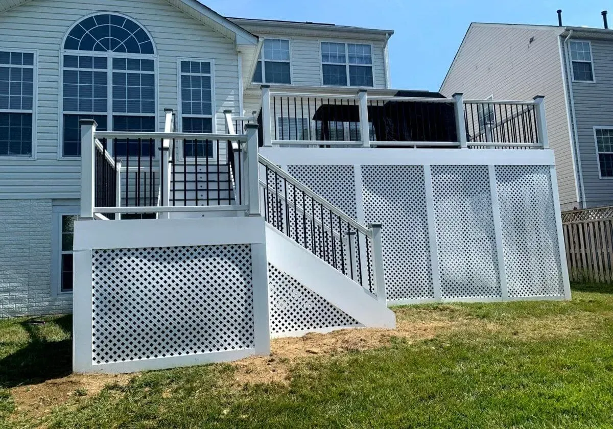 A large white deck with stairs is in the backyard of a house.