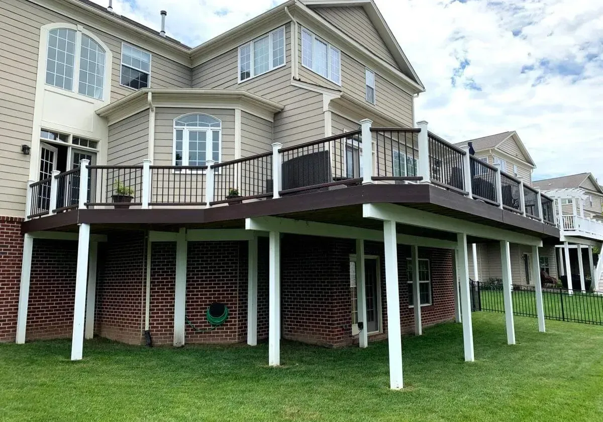 A large house with a large deck on the back of it.