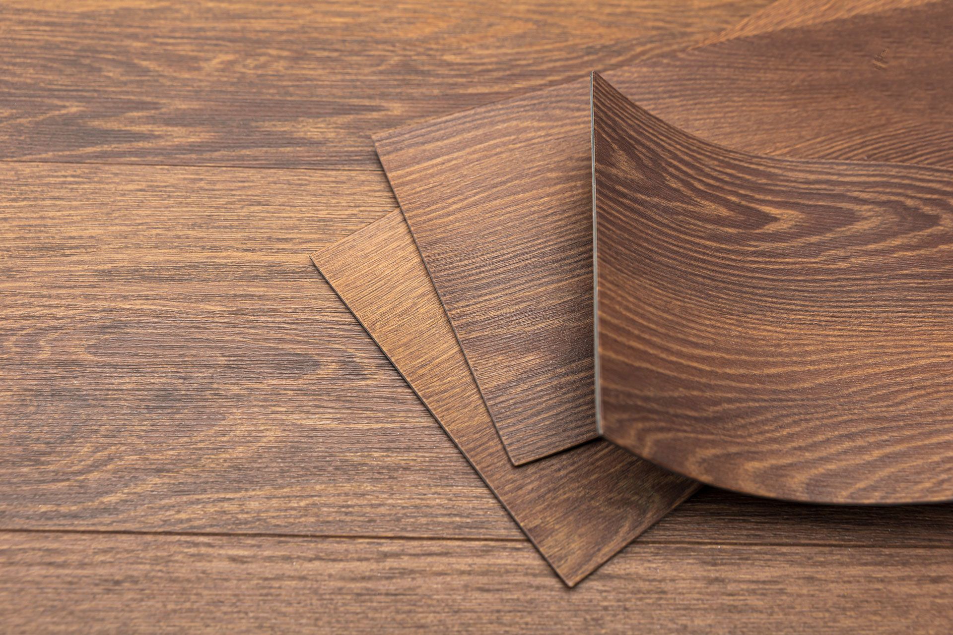 Three brown wood planks overlapping a wooden surface.