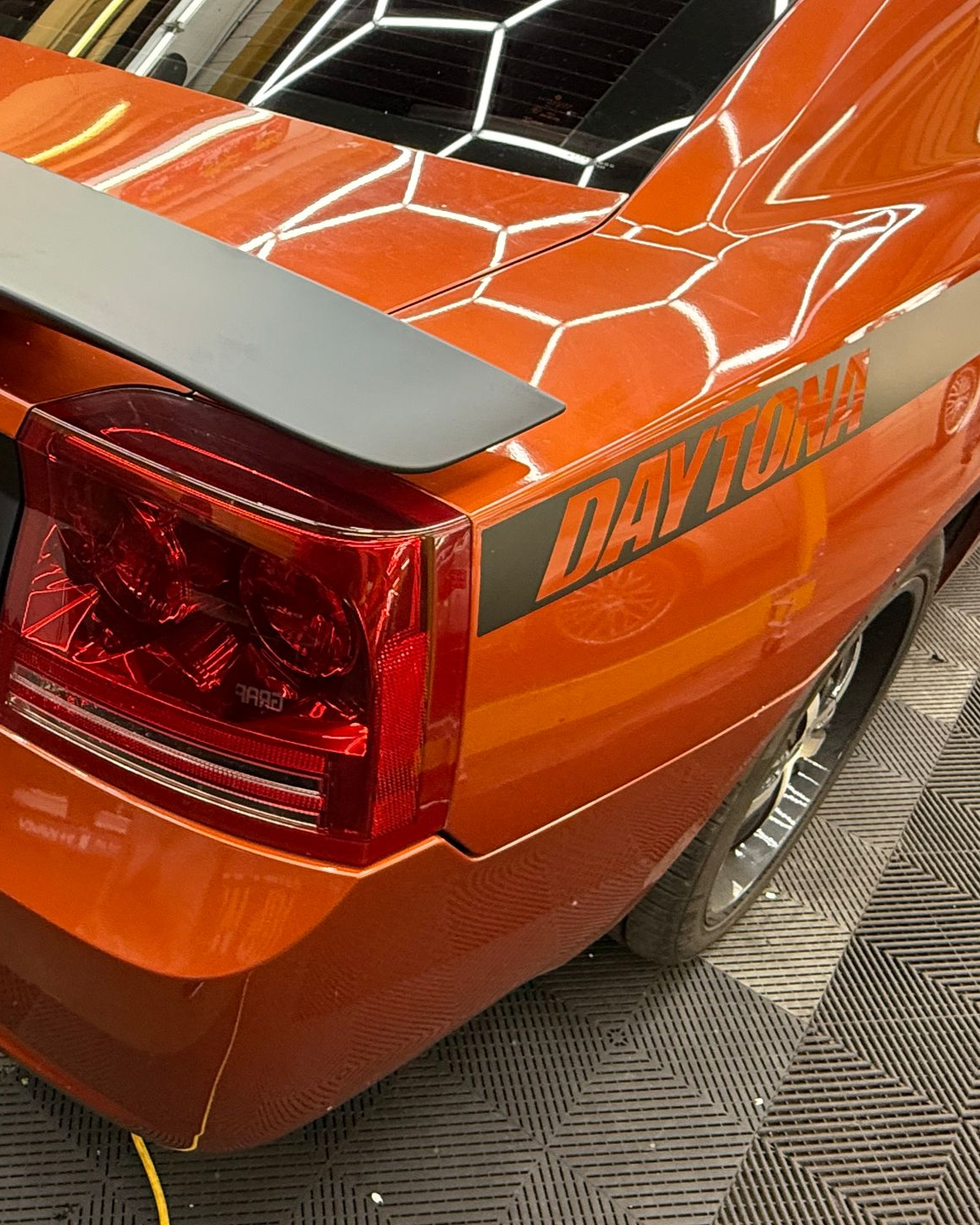 Orange Dodge Charger Daytona, gray spoiler, black and gray side stripes, taillight.