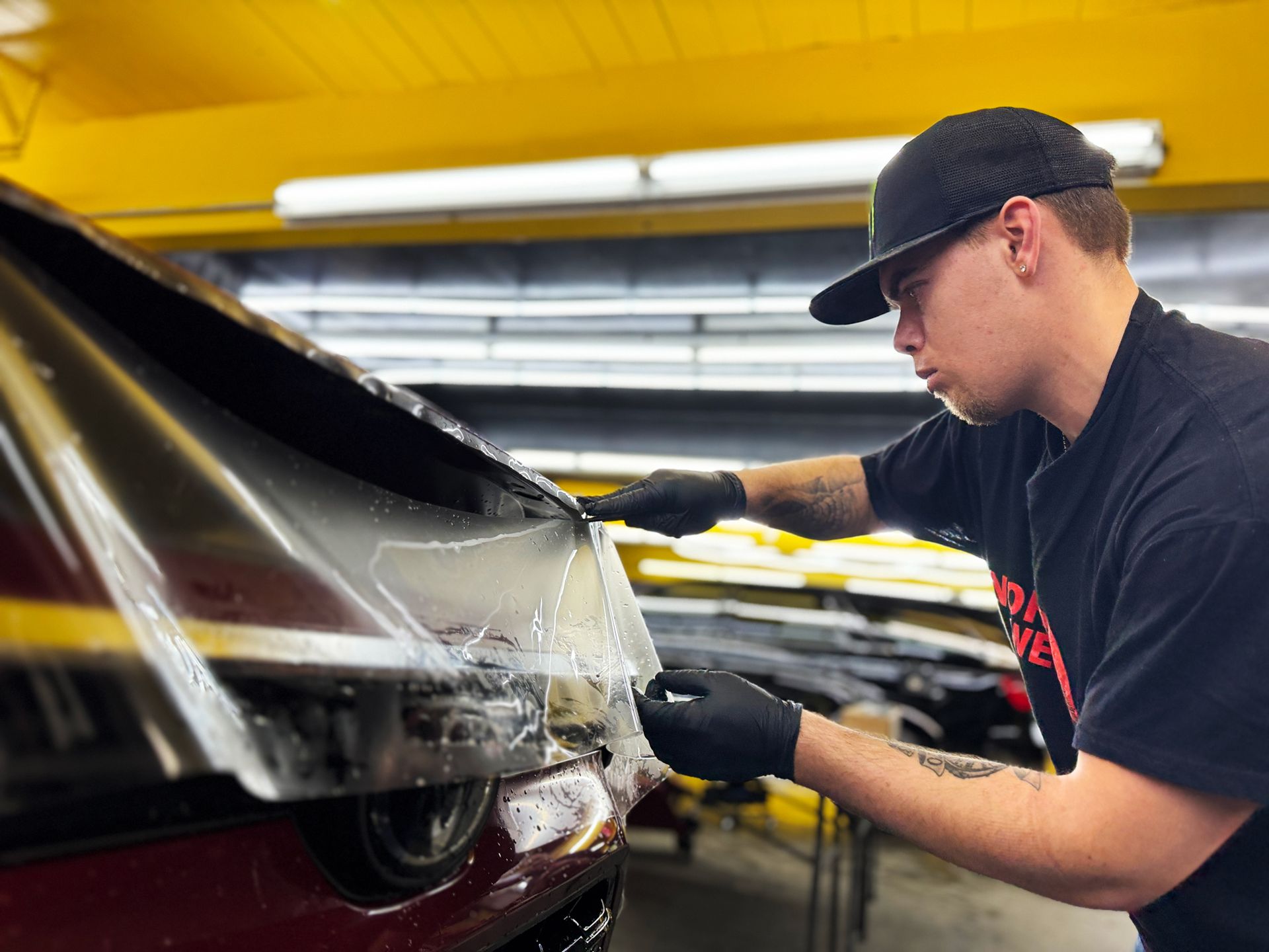 A man is wrapping a car in plastic in a garage.