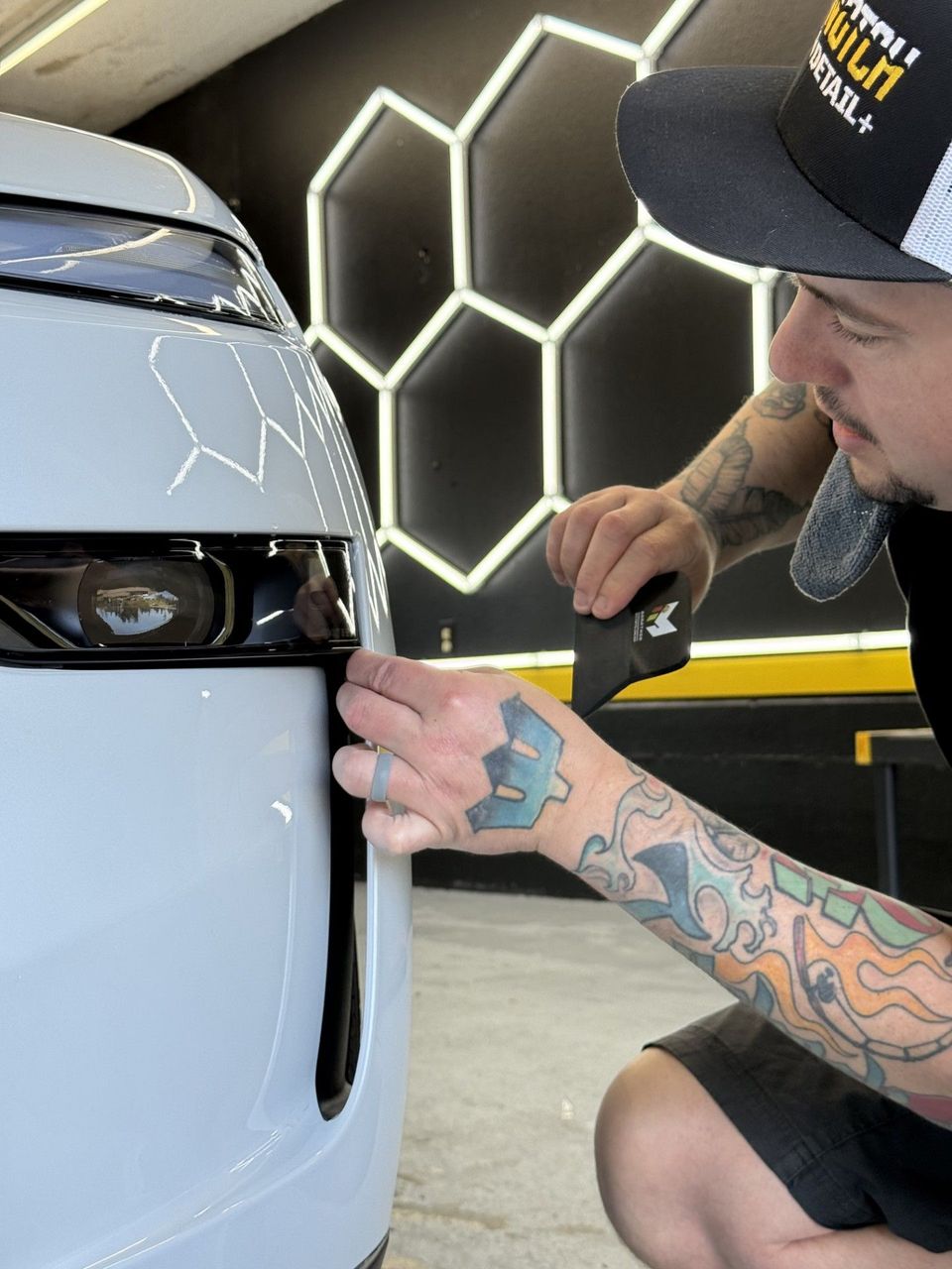 A man with a tattoo on his arm is installing PPF on a car