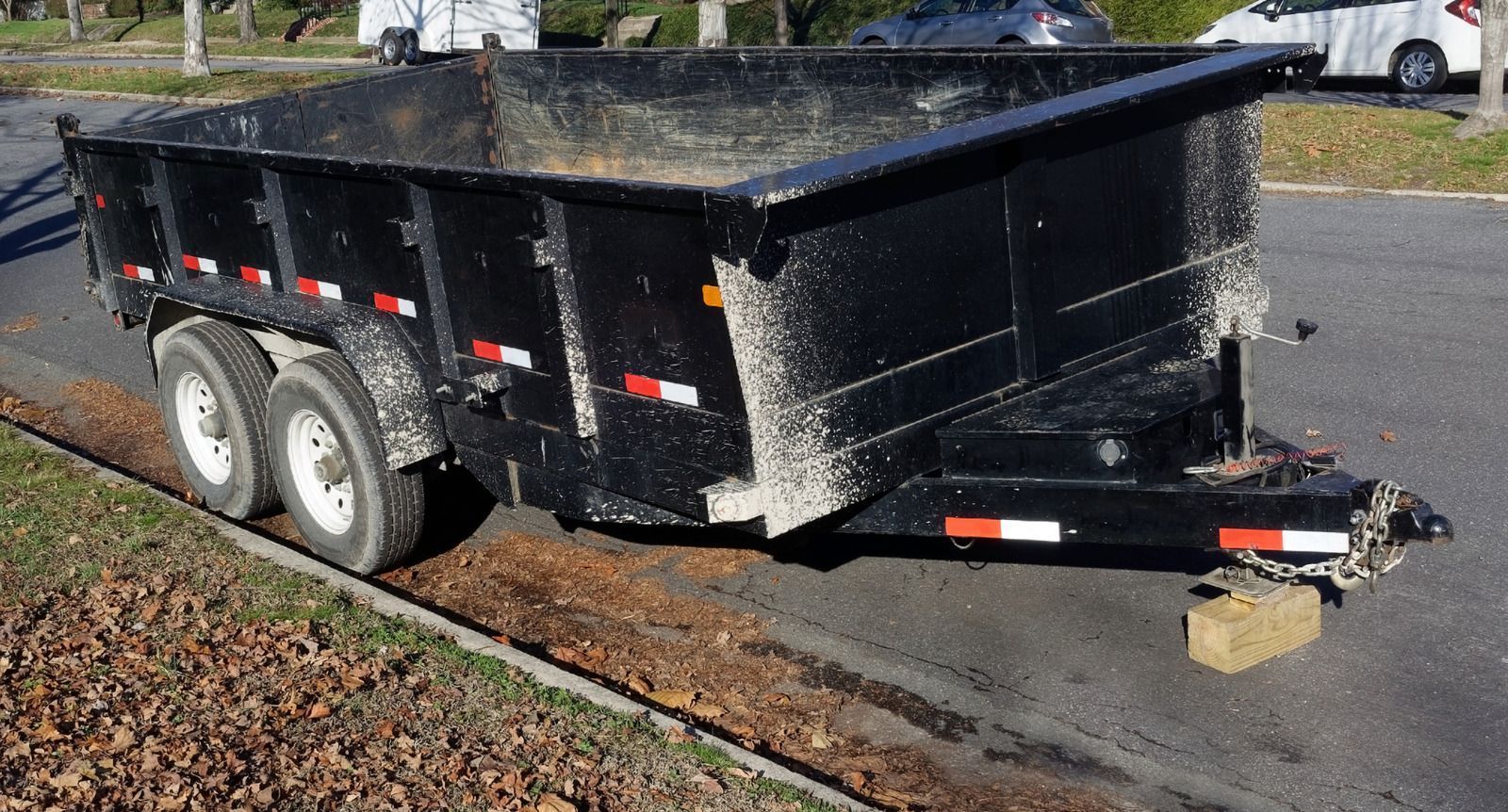 A dumpster trailer is parked on the side of the road.