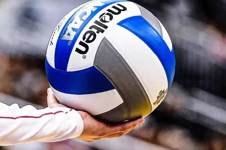Male and a female volleyball players jump to tip the ball.